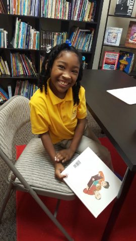 Smiling student holding a picture book in the academy's reading room