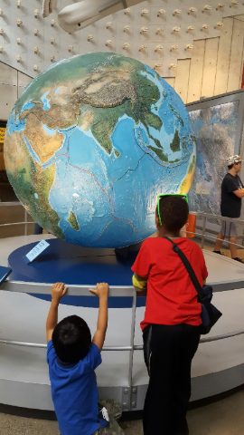 Two students studying a large relief globe at a science museum
