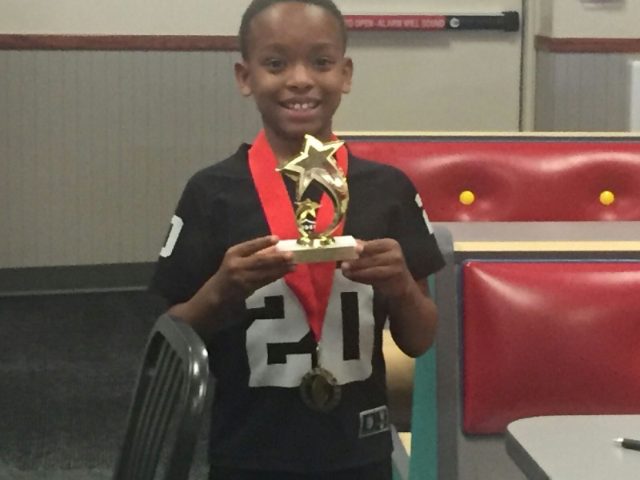 Student holding a gold star trophy and wearing a medal