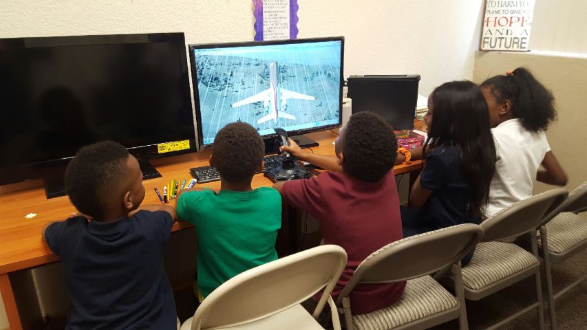 Students take turns using a joystick to fly a jet in a flight simulator program